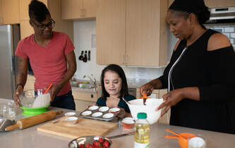 Three people preparing food in a kitchen. One is in a wheelchair.